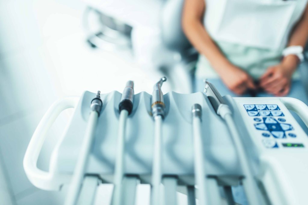 歯科の椅子に座っている患者の前に歯の治療器具が置かれている