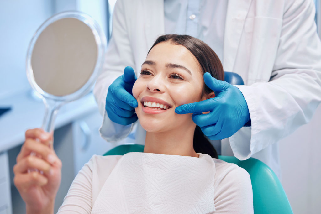 歯科医院で鏡を見て歯を確認する女性