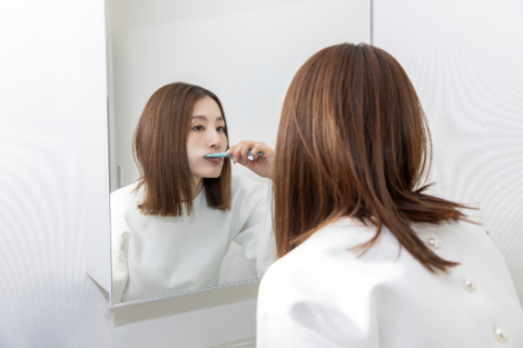 鏡を見ながら歯磨きをする女性