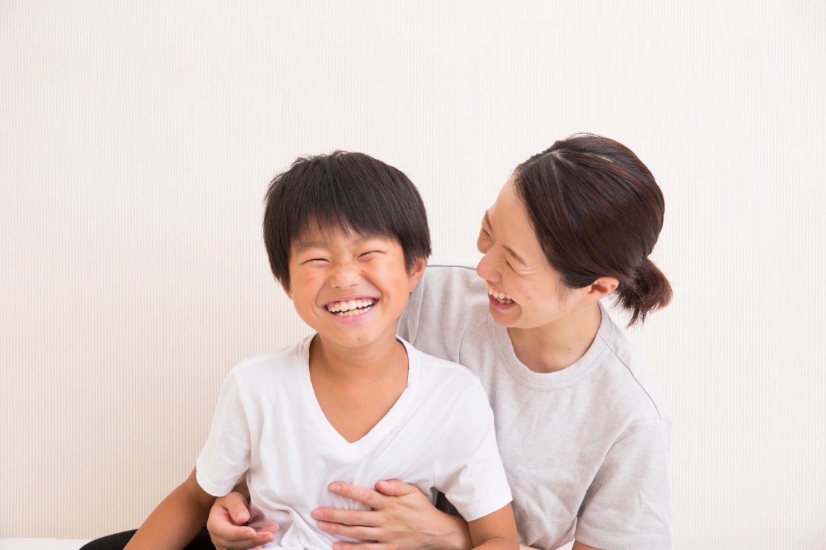 プレオルソで整った歯並びの子どもの顔を笑顔で覗き込む母親